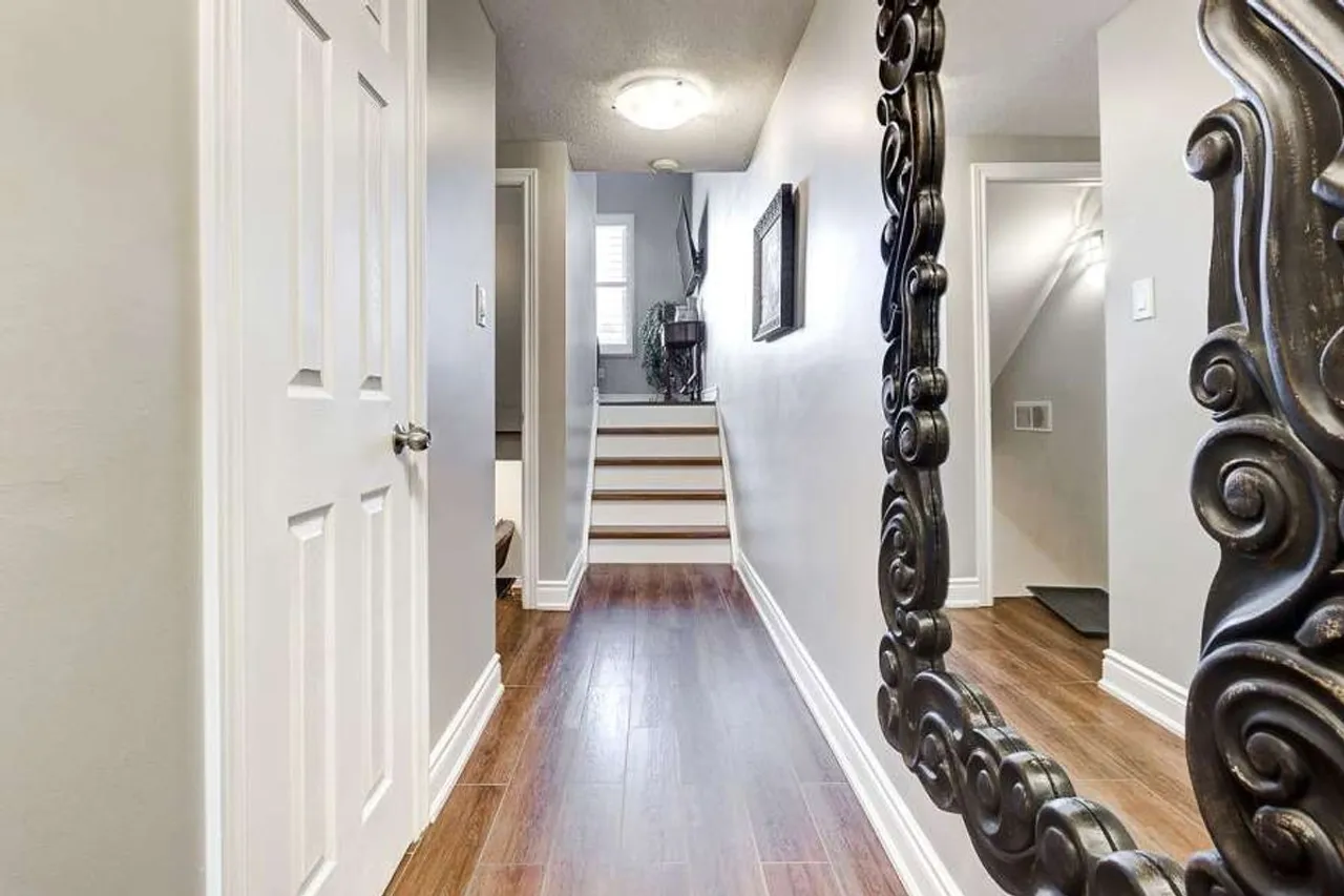 Main floor hallway leading to a staircase, with wood-look tile flooring