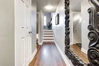 Main floor hallway leading to a staircase, with wood-look tile flooring