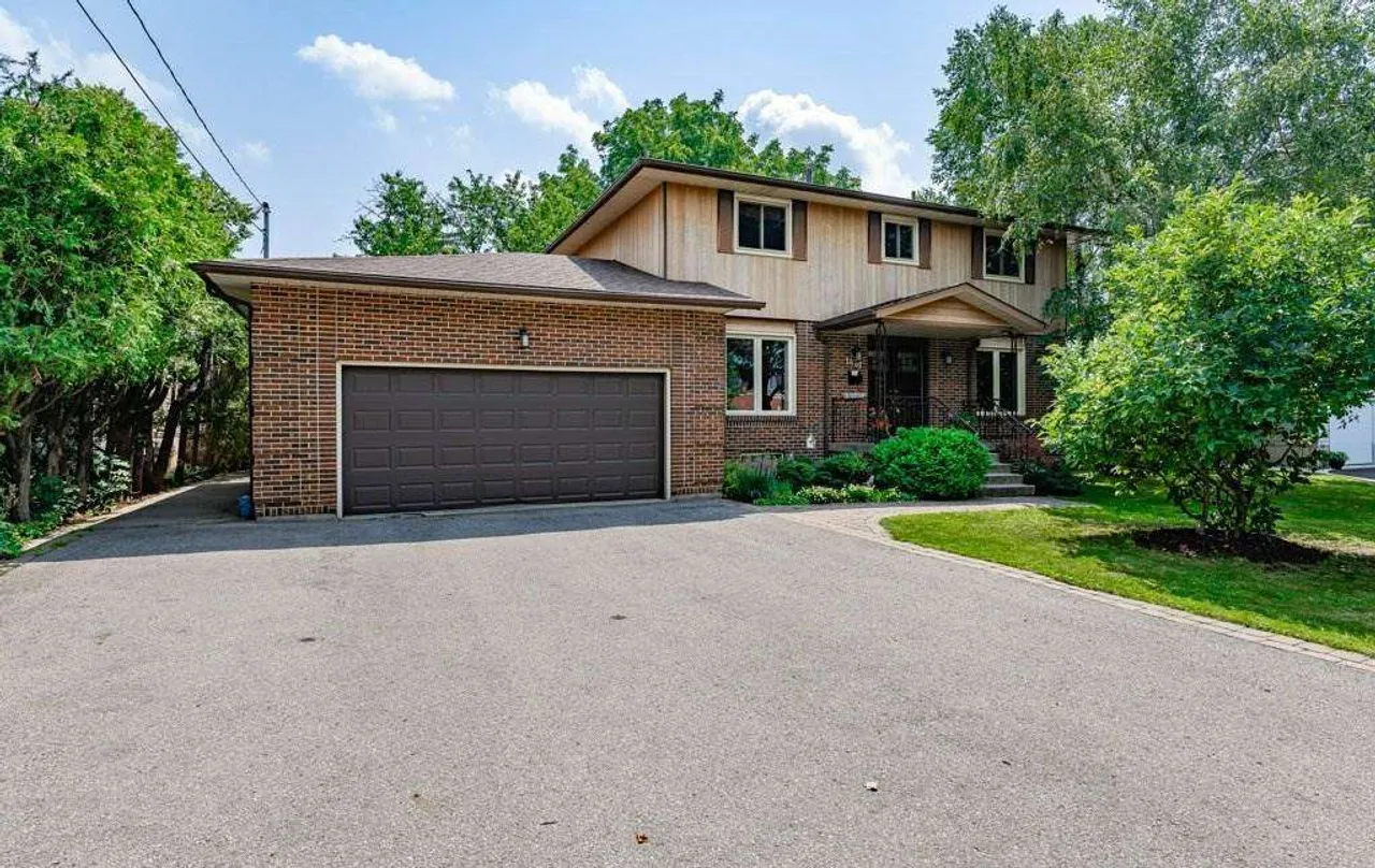 Front exterior of a two-storey brick and wood-sided home on Upper Wellington Street with a 6+ car driveway