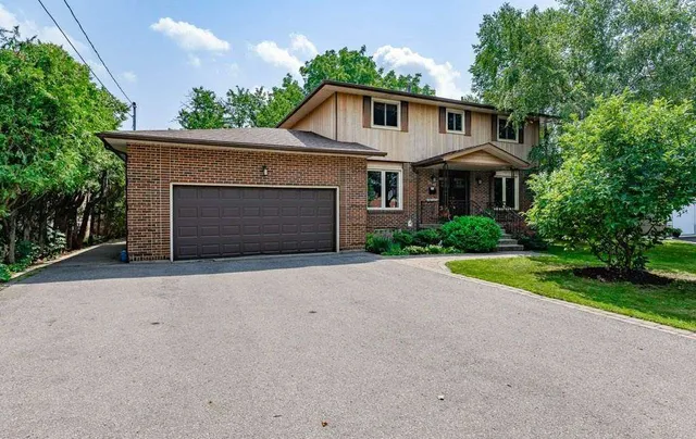 Front exterior of a two-storey brick and wood-sided home on Upper Wellington Street with a 6+ car driveway