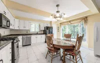 Eat-in kitchen with a wood dining set and walkout to a sunroom addition