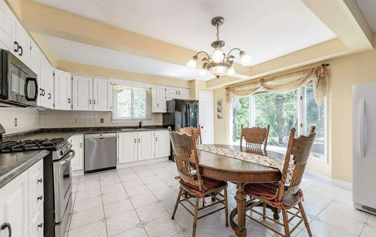 Eat-in kitchen with a wood dining set and walkout to a sunroom addition