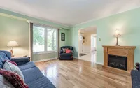 Living room with a green accent wall, oak fireplace mantel, and hardwood floors