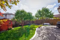 Backyard with mature fruit trees, a garden shed, and a stone patio