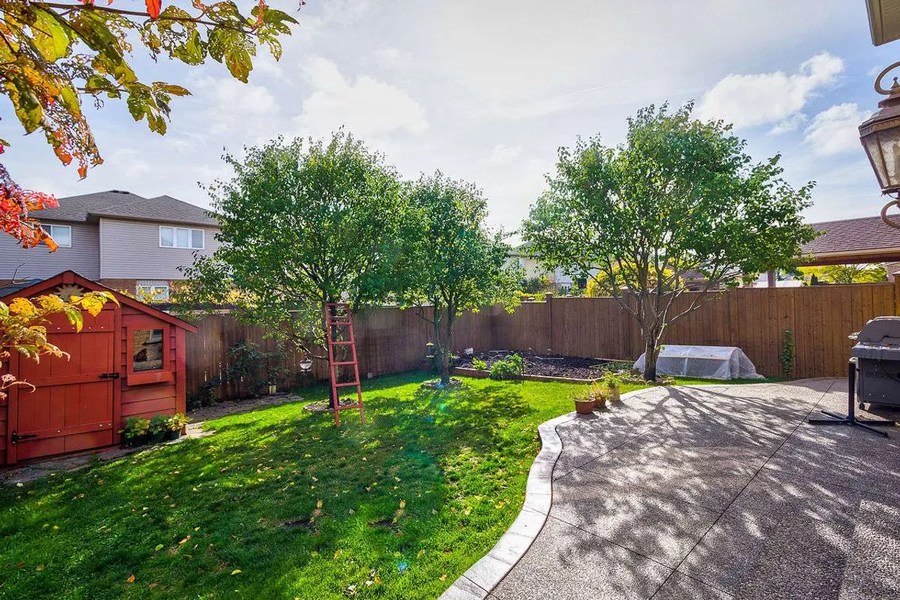 Backyard with mature fruit trees, a garden shed, and a stone patio