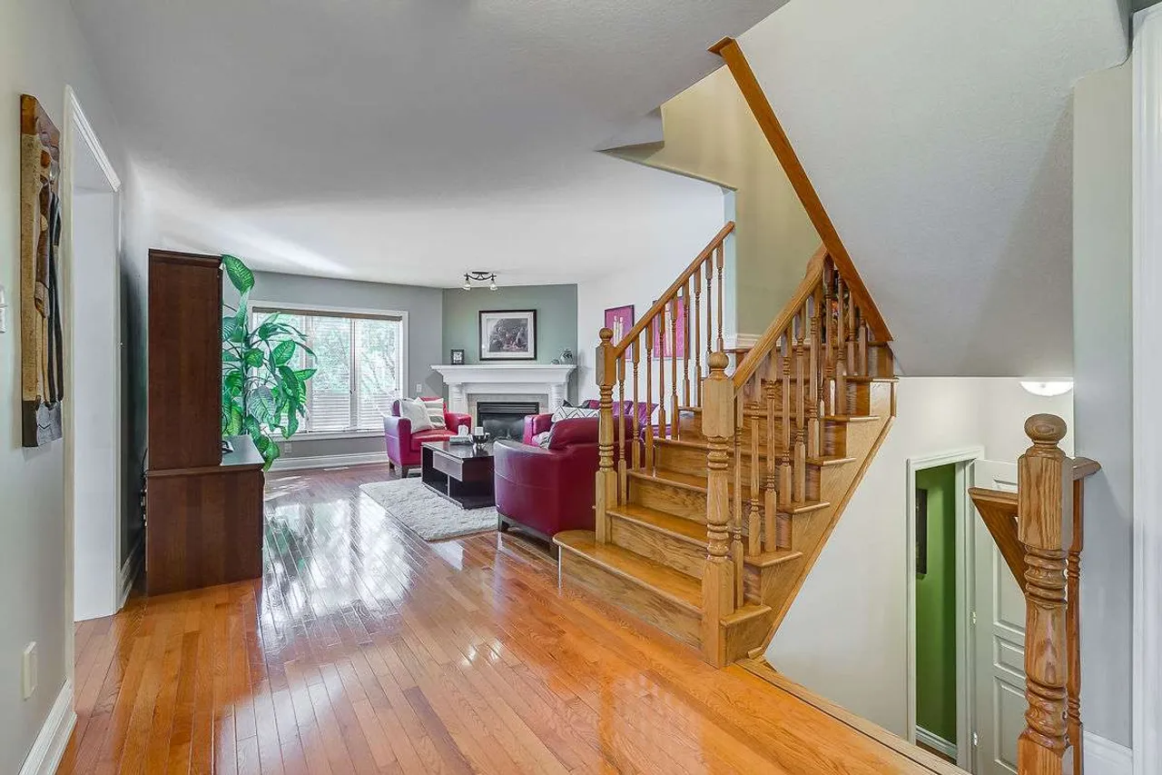 Foyer with an oak staircase and a view into the living room with a fireplace