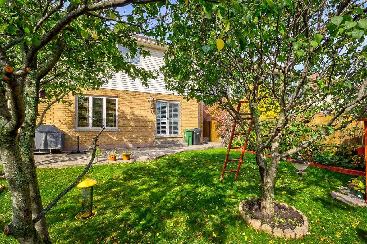 Rear exterior with a stone patio and mature backyard trees