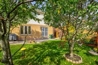 Rear exterior with a stone patio and mature backyard trees