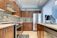 Maple kitchen with stone backsplash and stainless steel appliances