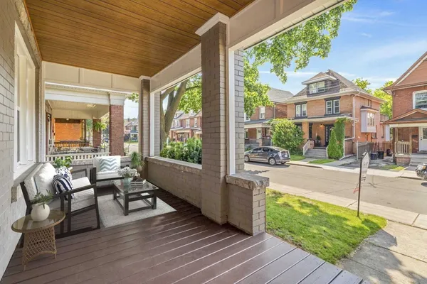 Covered front porch with seating, on a tree-lined Hamilton street