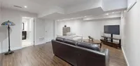 Finished basement recreation room with wide-plank flooring and pot lights
