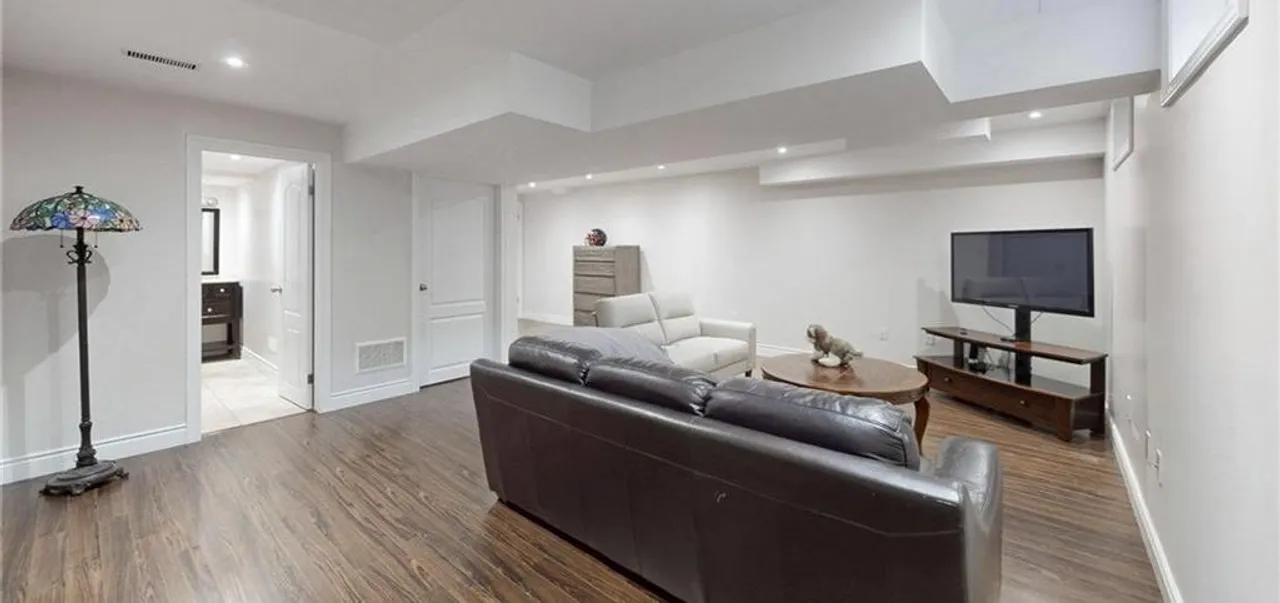 Finished basement recreation room with wide-plank flooring and pot lights
