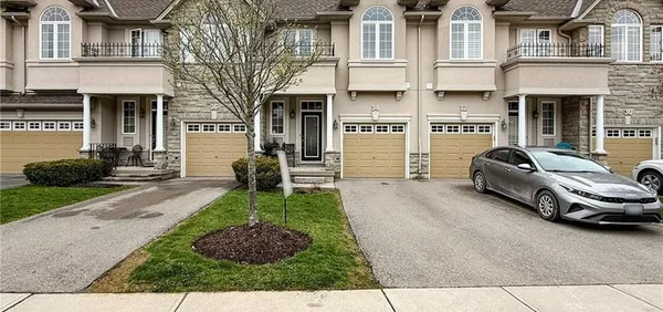 Front exterior of a two-storey brick-and-stucco townhome at 34 Forest Valley Crescent with an attached garage and interlock driveway