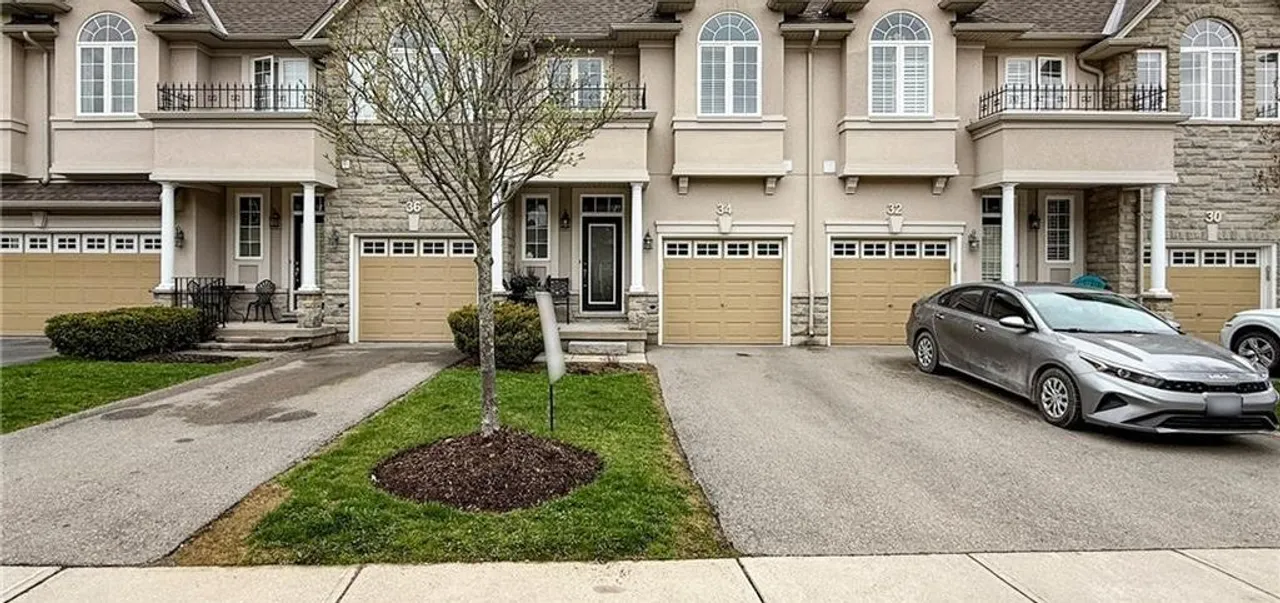 Front exterior of a two-storey brick-and-stucco townhome at 34 Forest Valley Crescent with an attached garage and interlock driveway