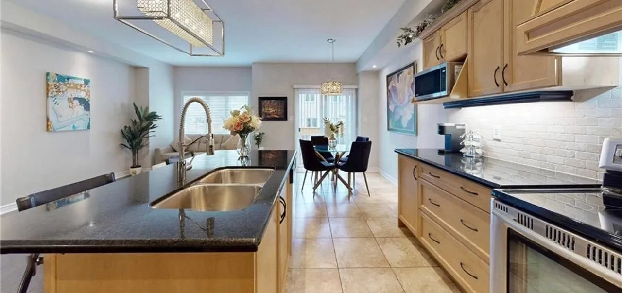 Open-concept kitchen with granite countertops, stainless steel appliances, and a view through to the dining and living areas
