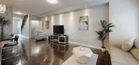 Spacious living room with dark hardwood floors, recessed lighting, and an open staircase to the upper level
