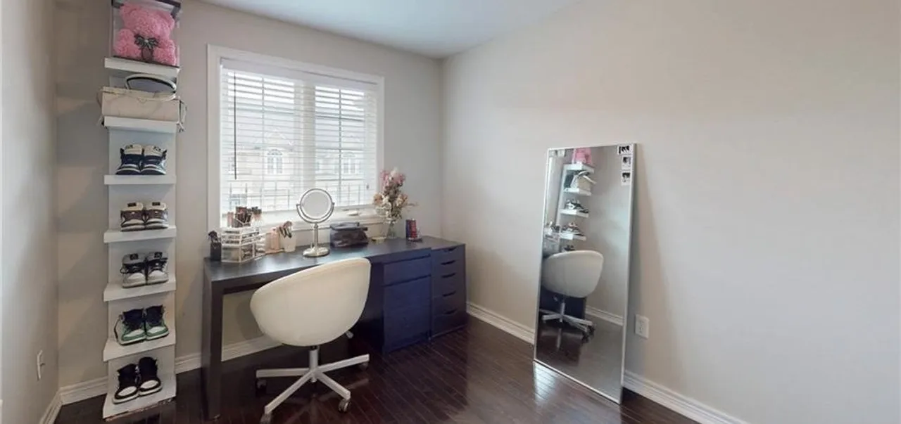 Primary bedroom with a large window and dark hardwood flooring