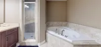 Primary ensuite featuring a jacuzzi soaker tub and a separate glass shower
