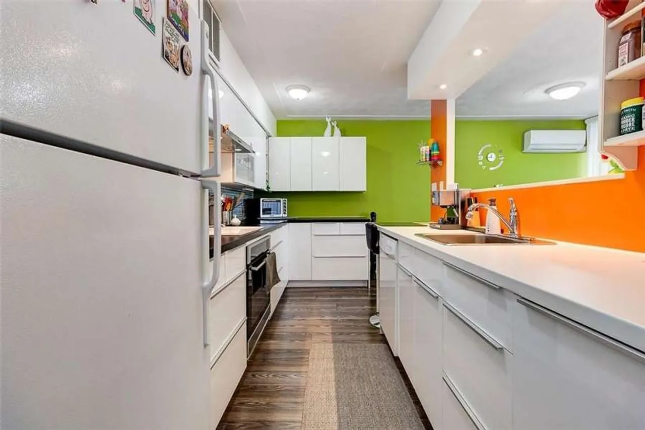 Renovated open-concept kitchen with bright green and orange accent walls