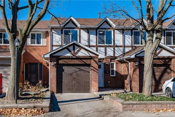 Front exterior of a Tudor-style brick townhouse on Longmoor Drive in the Strathcona Gardens community of Burlington