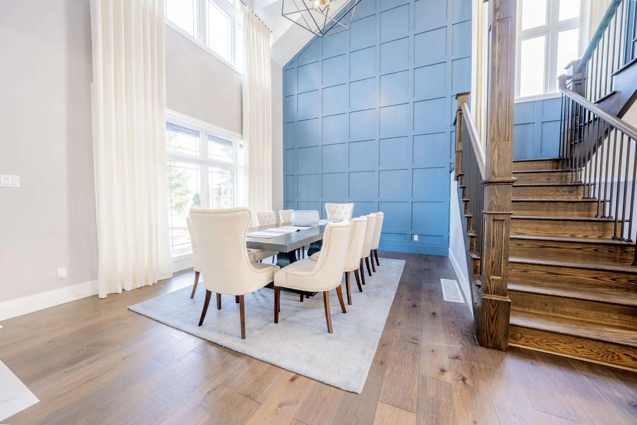 Two-storey dining room with a floor-to-ceiling blue panelled accent wall and open staircase