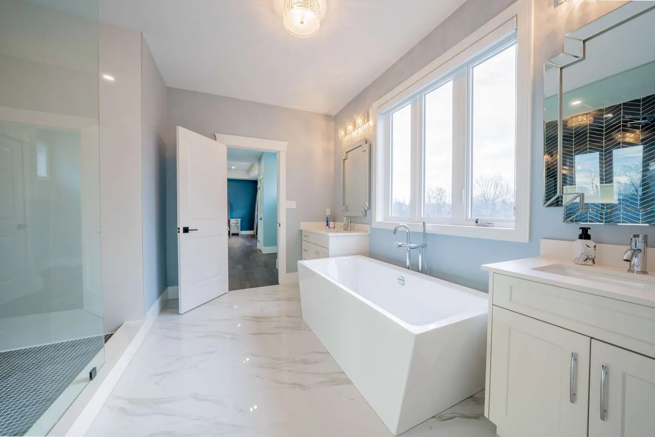 Primary ensuite with a freestanding soaker tub, dual vanity, and glass shower