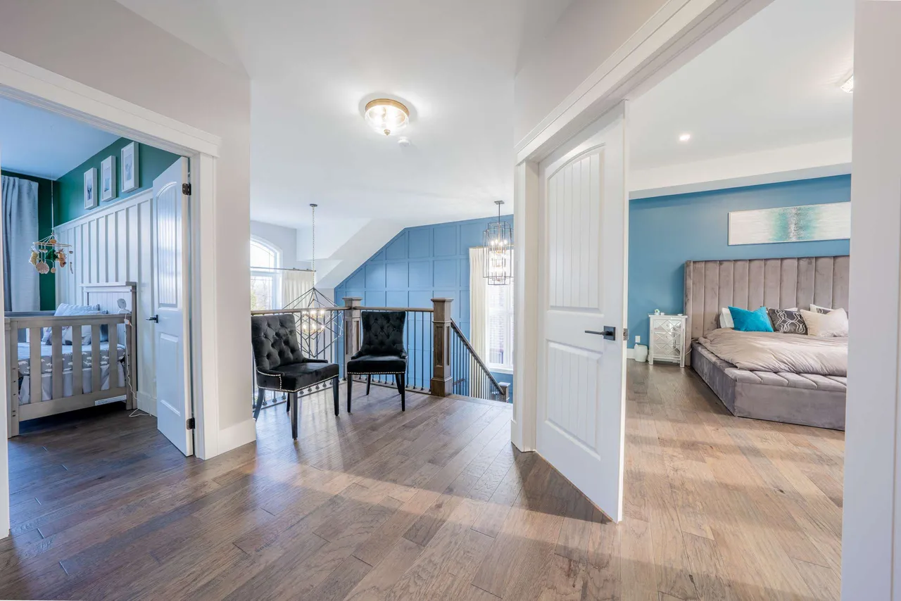 Upper-level hallway with a blue accent wall, leading to the primary suite