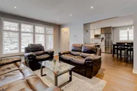 Open-concept living room with leather sofas, opening to the kitchen and dining area