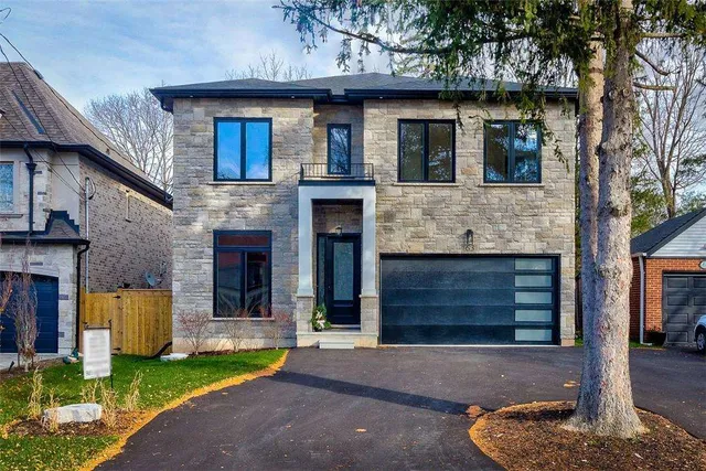 Front exterior of a custom-built stone and brick two-storey home on Hillside Avenue North with an oversized glass-panel garage door