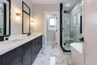 Primary ensuite with a marble-tiled glass shower, freestanding soaker tub, and dual vanity