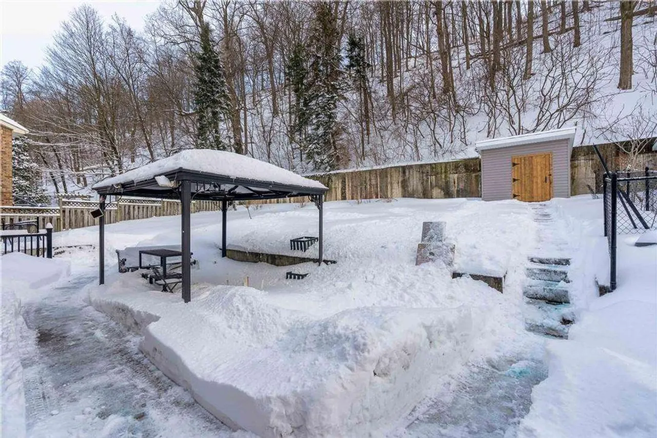 Snow-covered backyard with a gazebo and storage shed