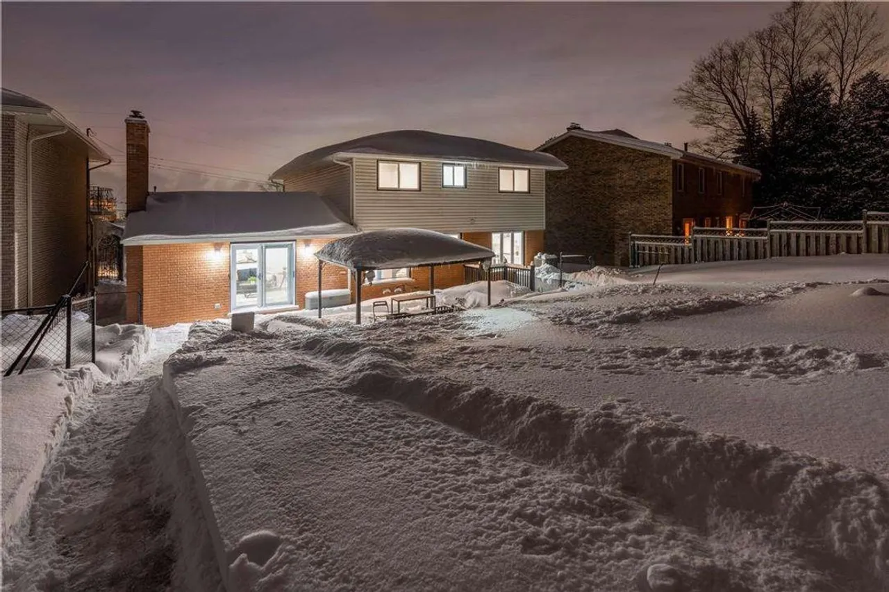 Rear exterior of the home covered in snow, backing onto the escarpment