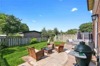 Backyard patio seating area with mature trees and a storage shed