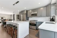 Updated eat-in kitchen with a grey island, stainless steel appliances, and pendant lighting