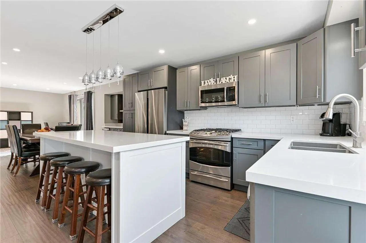 Updated eat-in kitchen with a grey island, stainless steel appliances, and pendant lighting