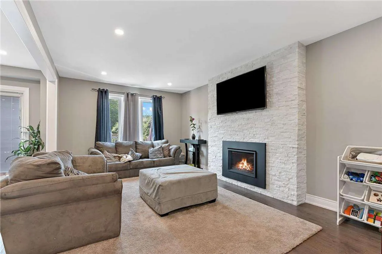 Living room with a stacked stone fireplace and wall-mounted TV