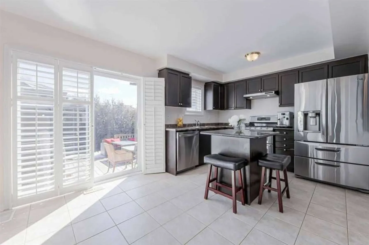 Kitchen with dark cabinetry, centre island, and walkout to the backyard