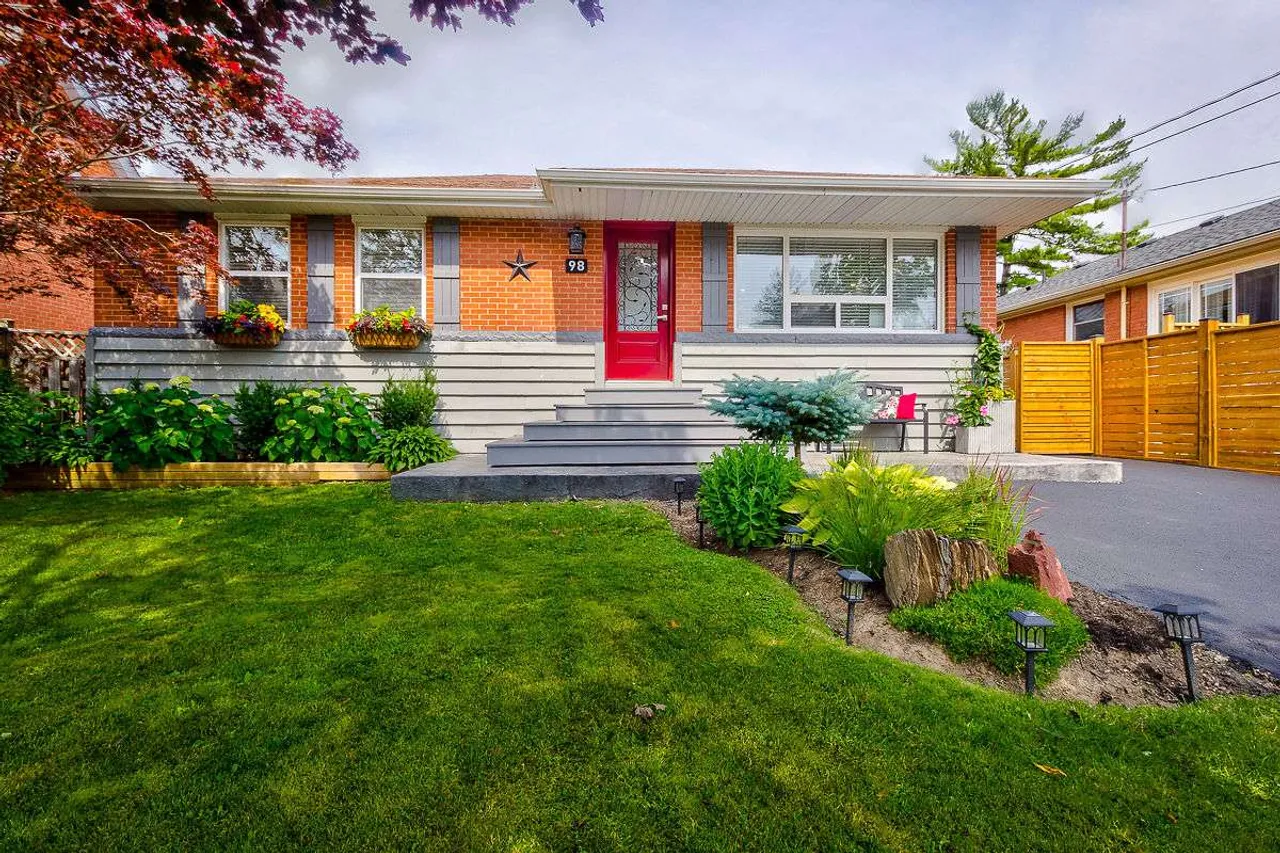 Front exterior of a renovated brick bungalow on Hardale Crescent with a red front door and landscaped entry