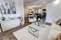 Staged main floor living room with a marble accent wall and glass coffee table