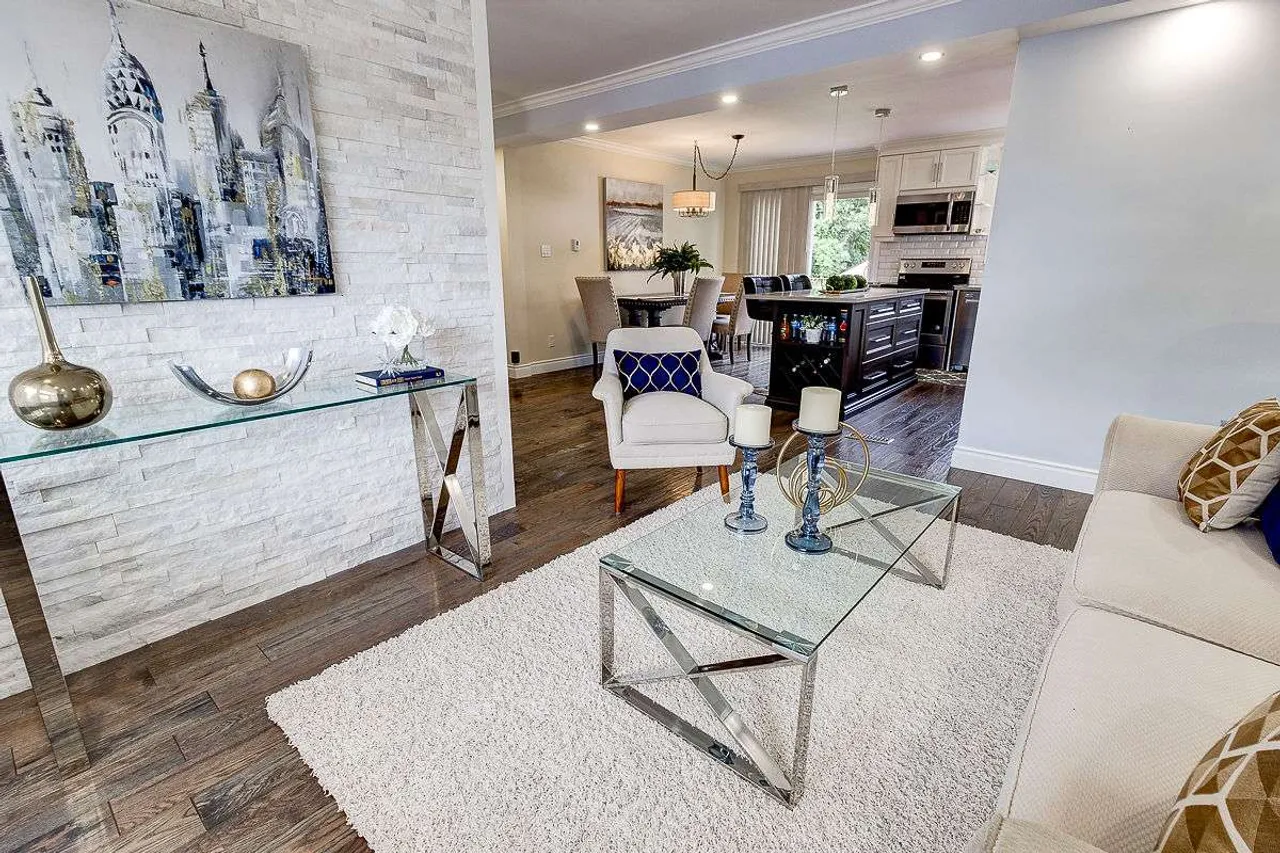 Staged main floor living room with a marble accent wall and glass coffee table